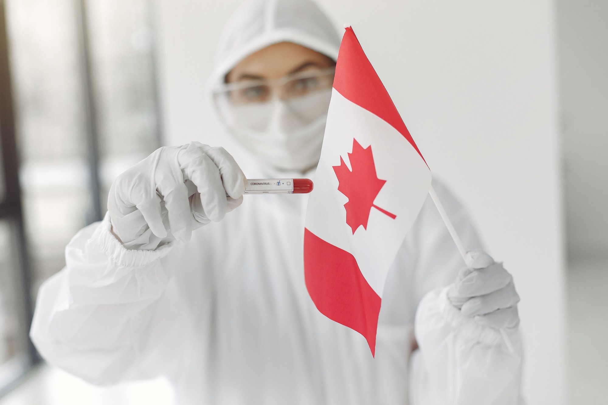 The scientist in coverall suit with a coronavirus sample and Canadian flag
