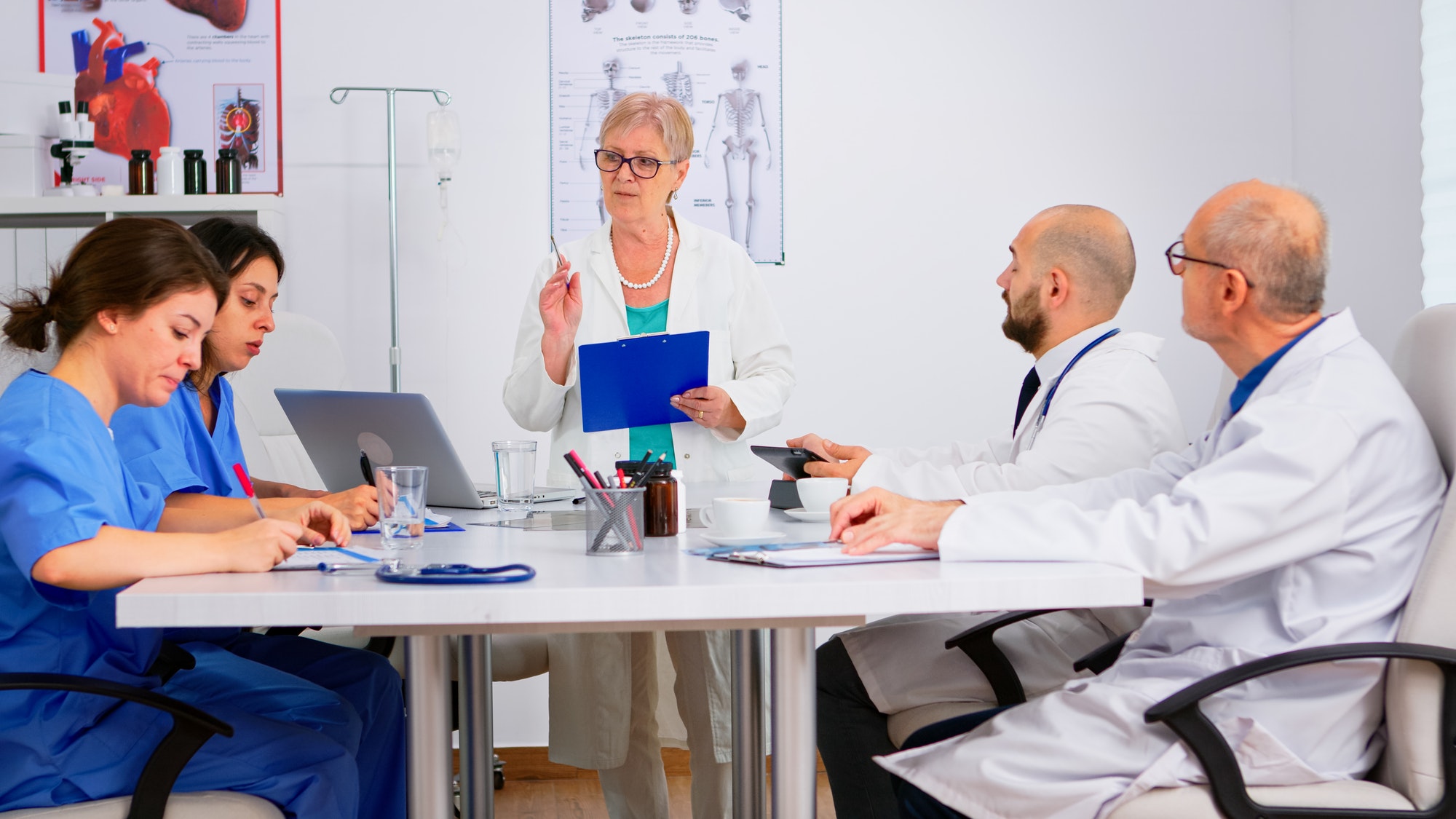 Mature doctor presenting new medical procedures standing at desk