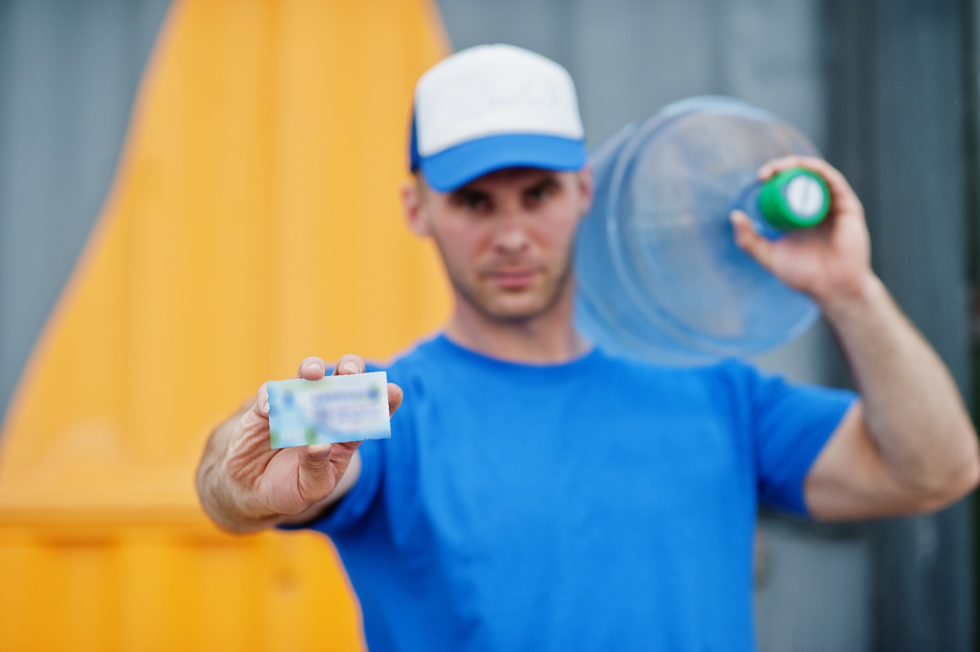 Delivery man carrying water bottle on shoulder and show business card.