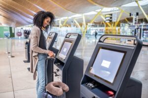 happy woman using the check-in machine at the airport getting th